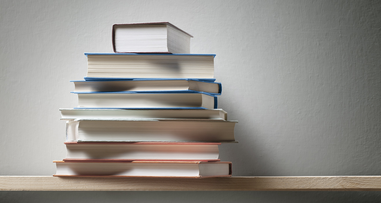 A student’s desk with a stack of books on it. 